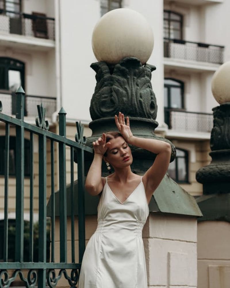 A woman in a beige dress standing beside a steel gate