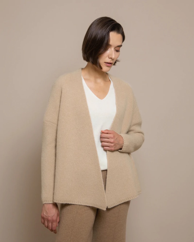 Esther Cardigan @ Francis Stories Woman wearing a beige coloured cardigan, with a white top and dark beige trousers
