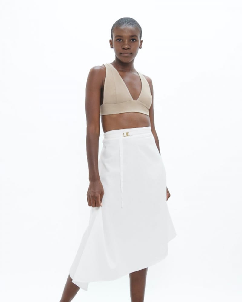 <em>Model dressed in white asymmetric skirt and light pink top.</em>