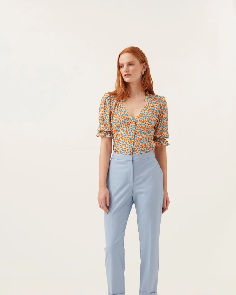 <em>Model dressed in pale sky-blue trousers, with orange patterned short sleeve blouse and orange sandals.</em>