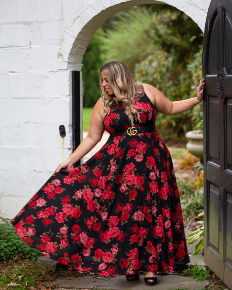 Woman standing outdoors in front of an open doorway wearing a long flowy dress