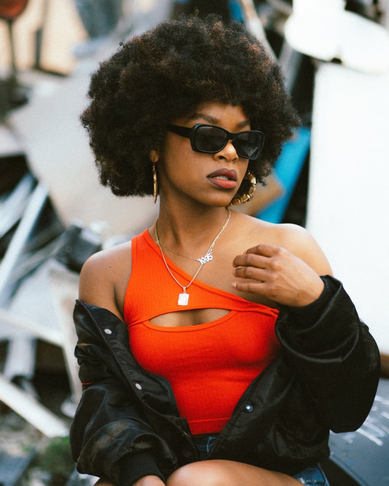 Girl wearing asymmetrical orange top and black jacket