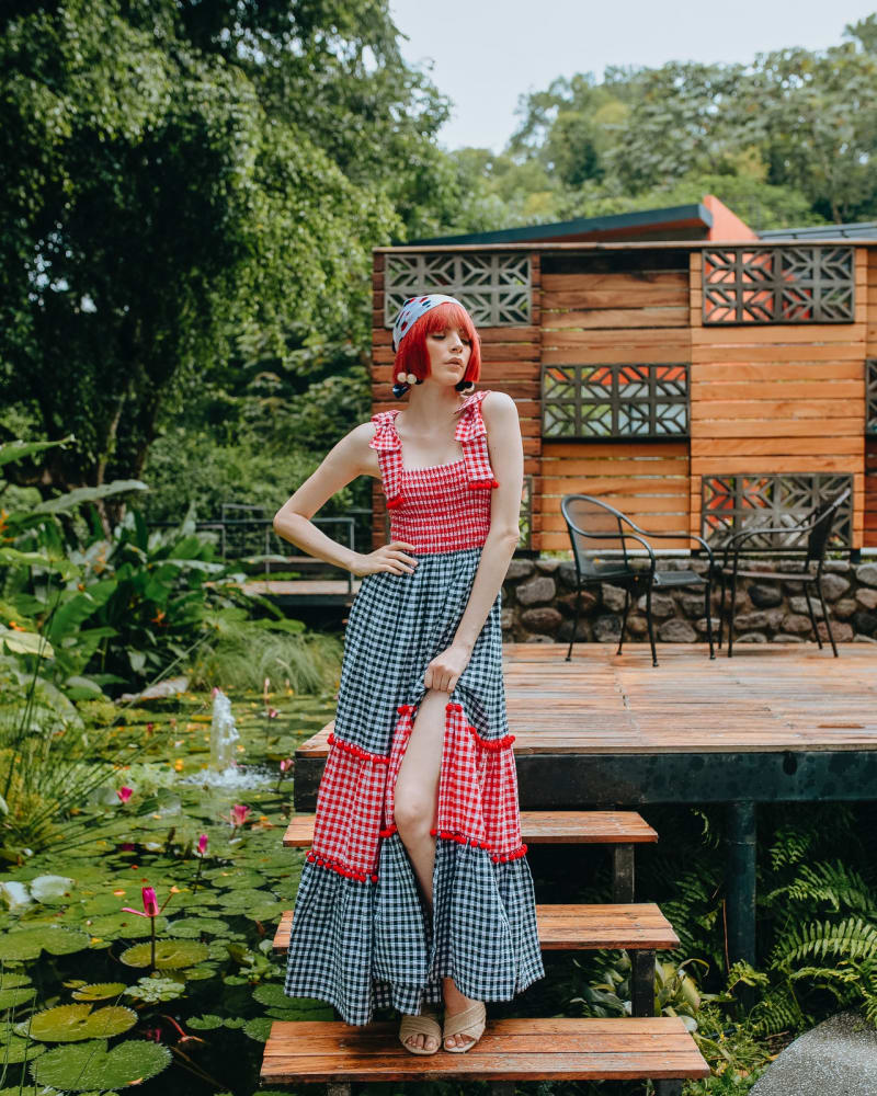 A woman in an outdoor setting wearing a checkered long maxi dress with a slit up one side