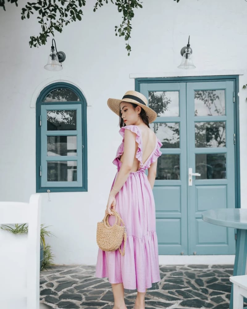 Woman in pink low back dress with straw hat and bag