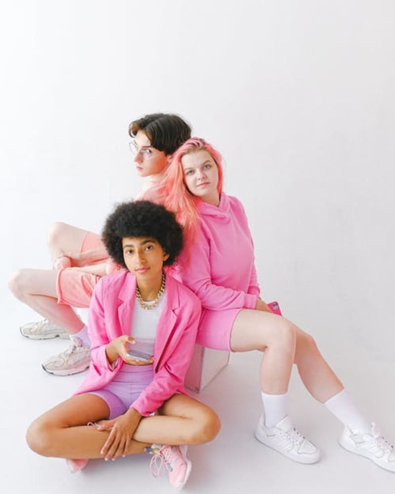 Three people sat back to back all dressed in different shades of pink