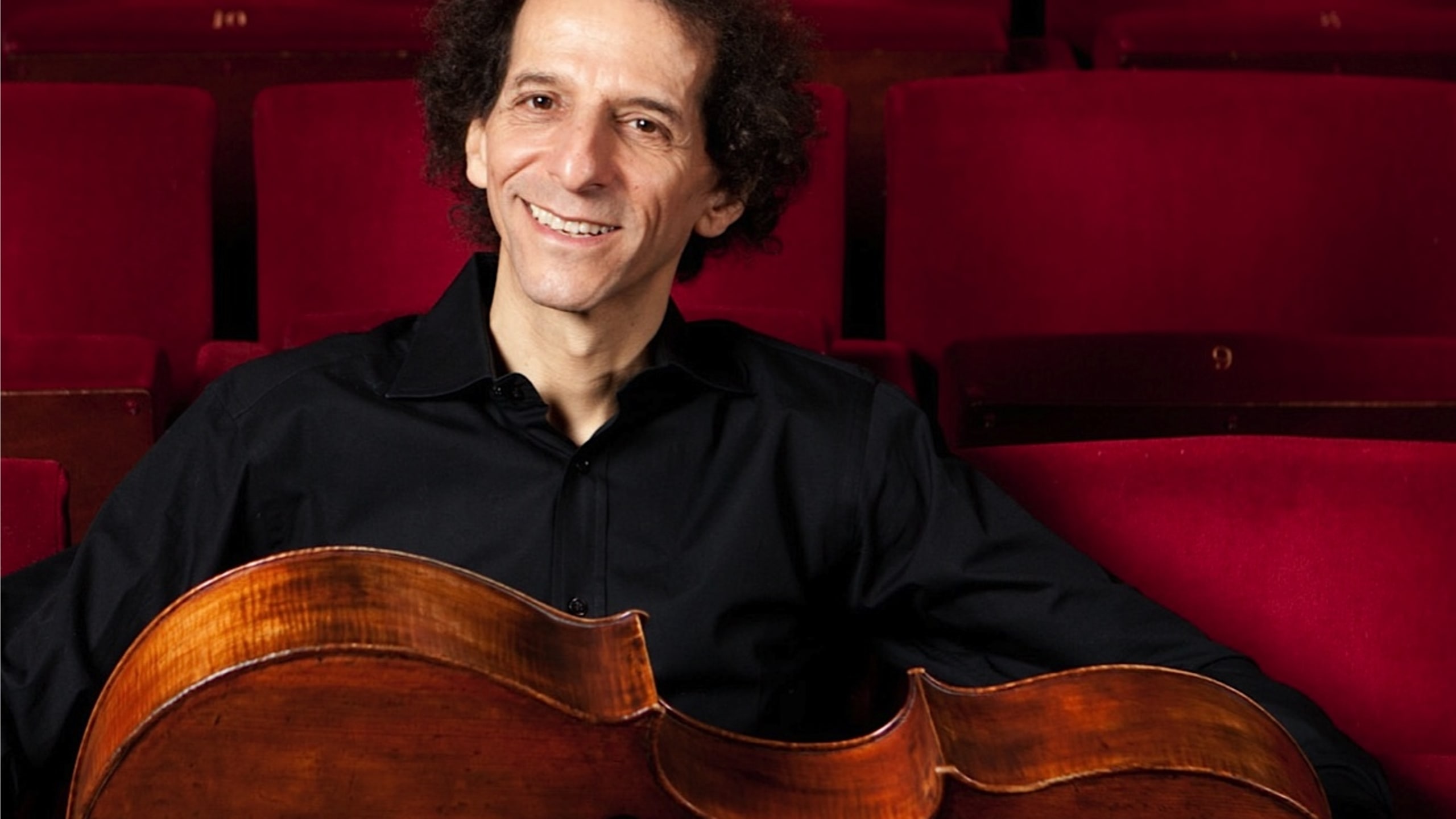 Colin Carr sitting in an auditorium with cell across his lap