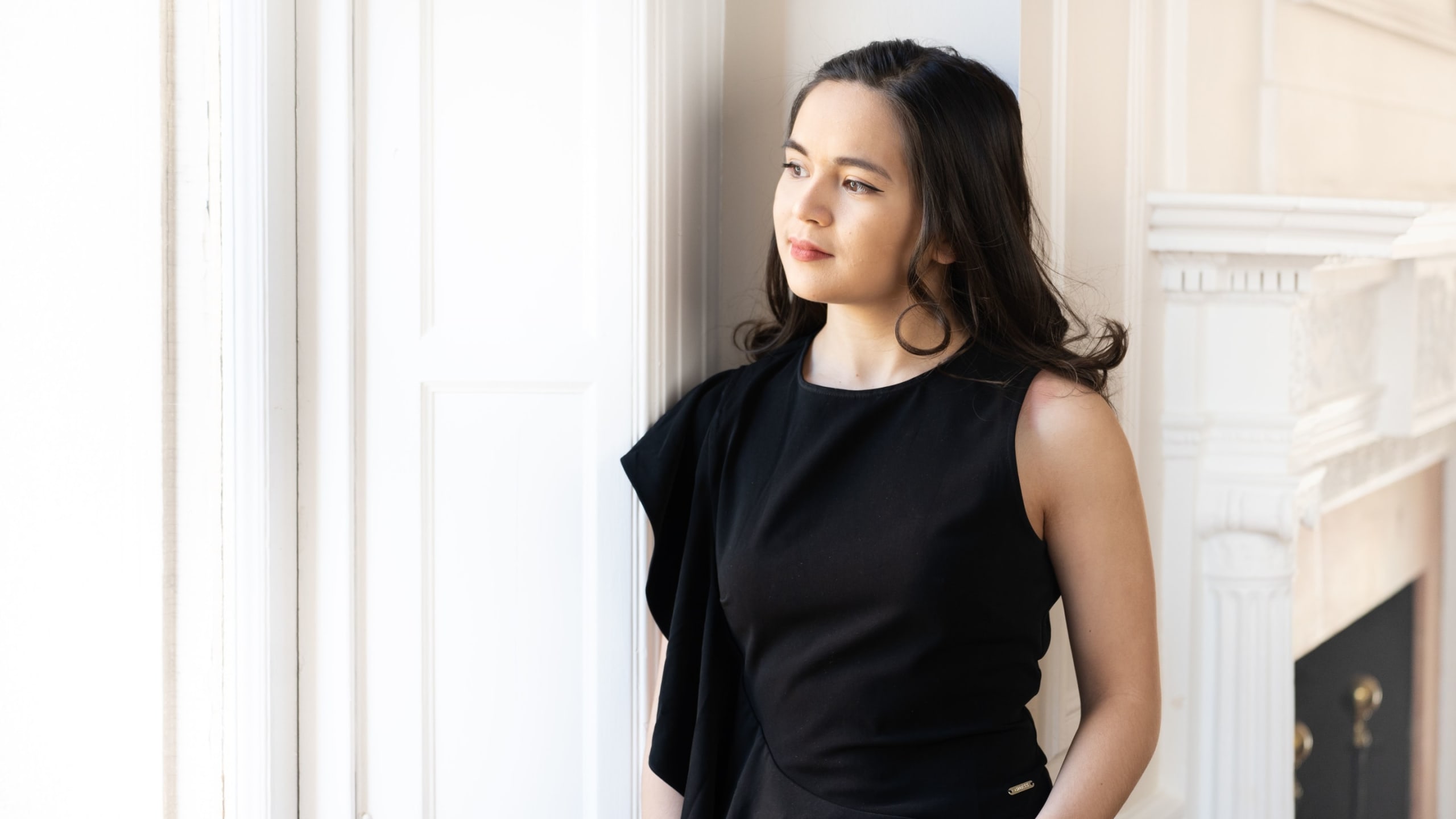 Portrait of Claire Thai looking out of a window.