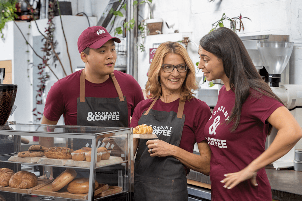 Coffee shop staff wearing custom hats, aprons, and t-shirts