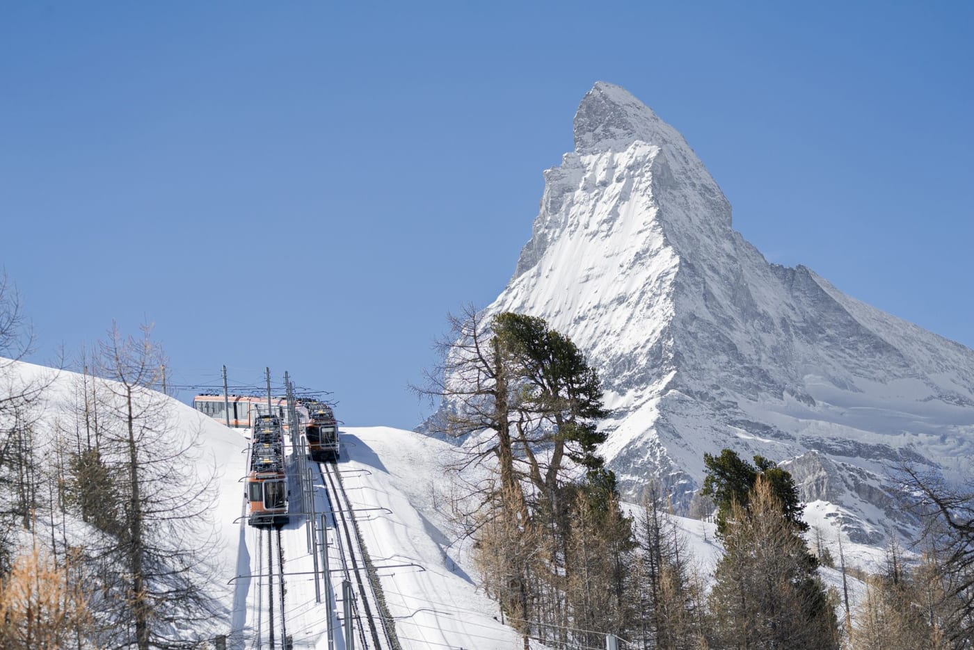 Zwei Züge der Gornergratbahn kreuzen sich auf der verschneiten Strecke hinauf zum Riffelalp, vor dem Matterhorn