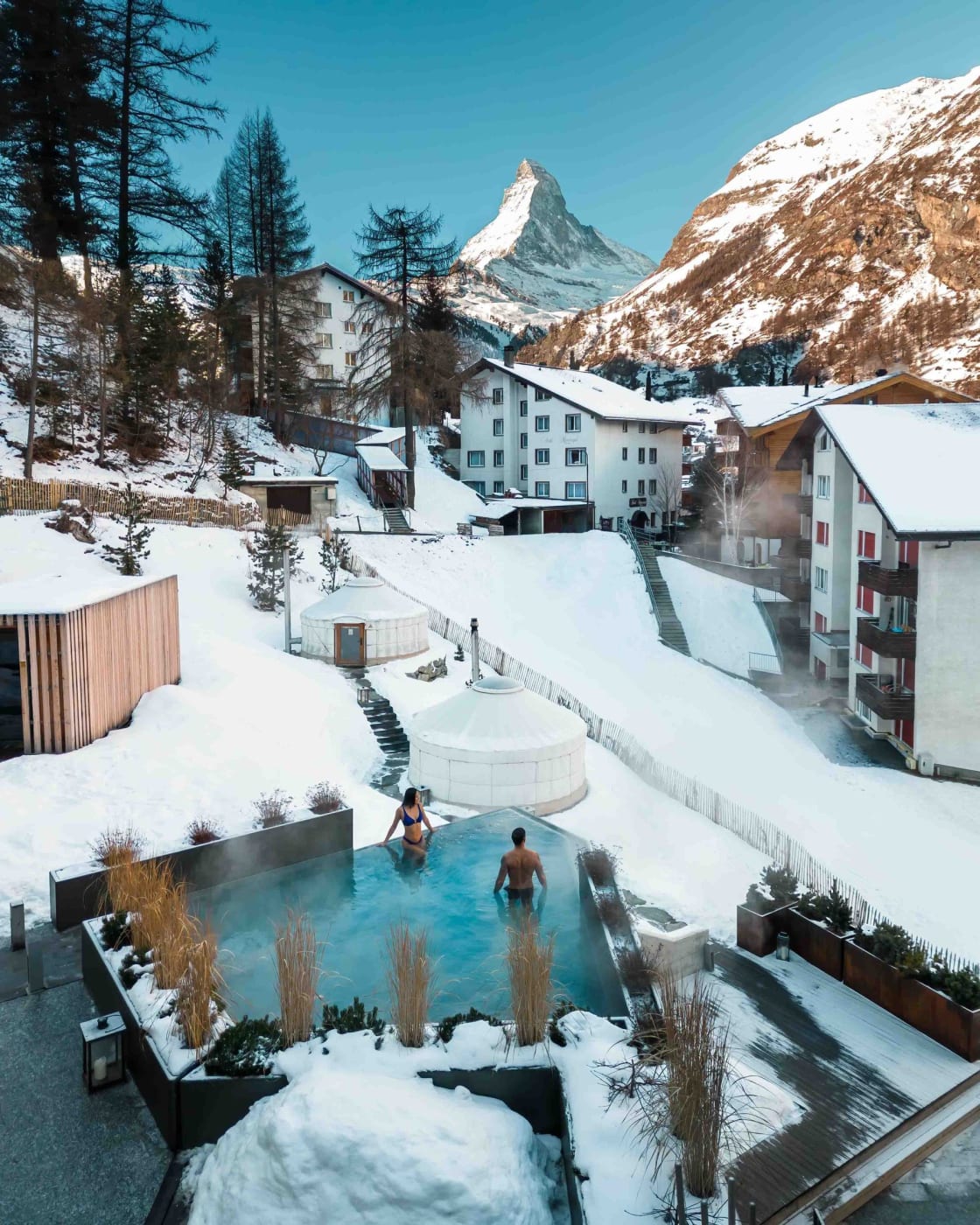 Das Außen-Onsen des Ātman Mountain Spa im CERVO Mountain Resort im Schnee, vor dem Matterhorn, oberhalb von Zermatt