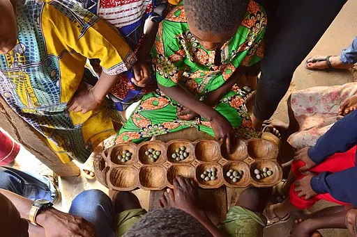 Children gather over a game of Ayo