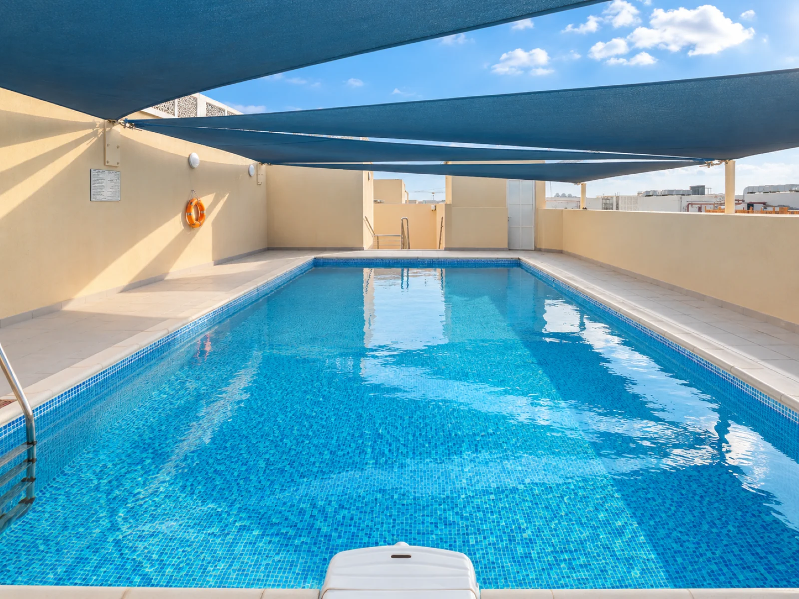 Sunny Rooftop Pool with Blue Shade Sails