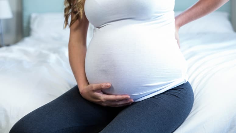 Pregnant woman grabbing her lower back in pain.