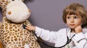 Child dressed up as a doctor examining his stuffed giraffe.