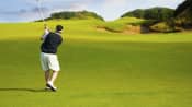 Man driving a golf ball on the golf course.