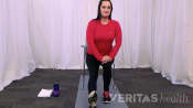 Woman sitting in a chair doing a hamstring stretch while her foot is outstretched.
