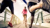 Group of runners running across a walking bridge.