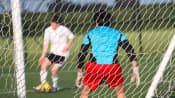 Goalie defending goal on a soccer field.