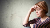 Teenage girl looking despondent and holding her forehead