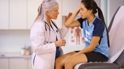 Teenage girl being examined by doctor for a concussion.
