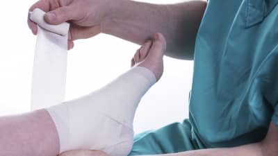 Patient having their ankle injury wrapped in an ace bandage.