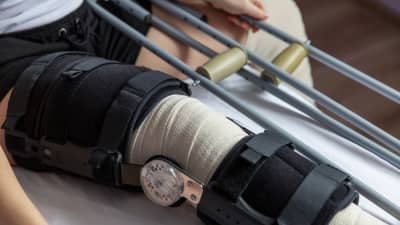Knee wrapped in a bandage with a brace and crutches.