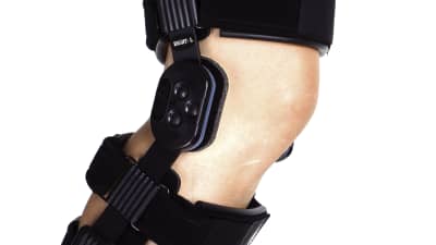Woman walking on crutches with a knee brace in recovery.
