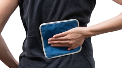 Man applying heat pack to the lower back.