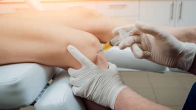 Patient receiving an injection in the knee joint.