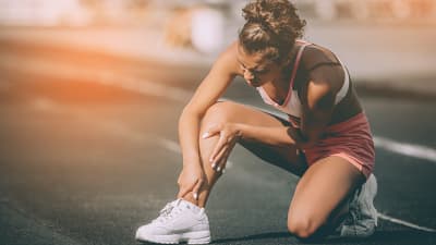 Woman grabbing calf in pain on a run.