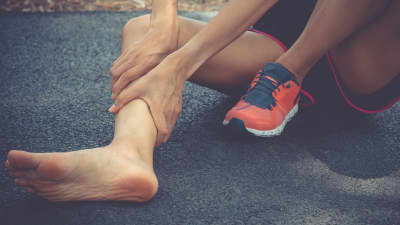 Woman runner holding shin in pain.