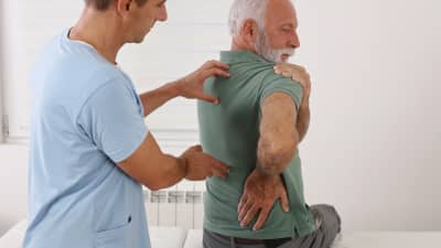 Doctor evaluating patient&#039;s spine and shoulder.