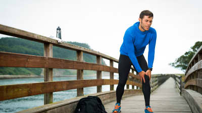 Man in workout clothes holding his knee in pain