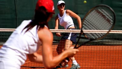 Woman holding her elbow in pain on the tennis court.