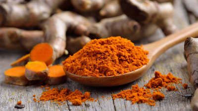 Wooden spoon full of turmeric