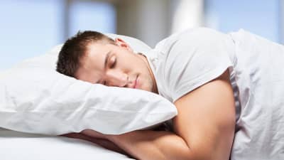 A man in bed sleeping on his stomach