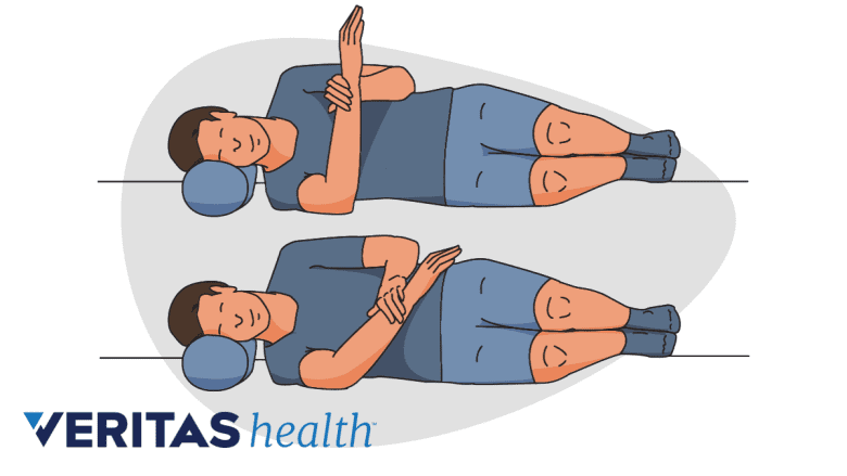 Performing the sleeper stretch for frozen shoulder.