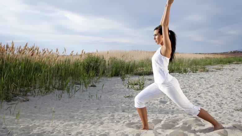 Woman performing yoga on the beach.