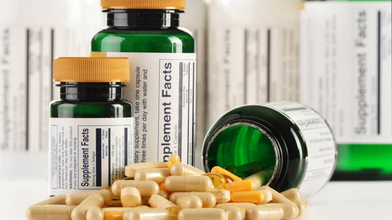 Supplement bottles with a few pills spilled out onto the table