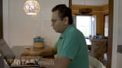 Man sitting at table in a chair to maintain good spinal posture and prevent neck pain and back pain.