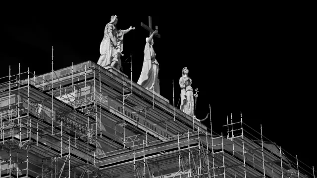Scaffolding around a building below statues