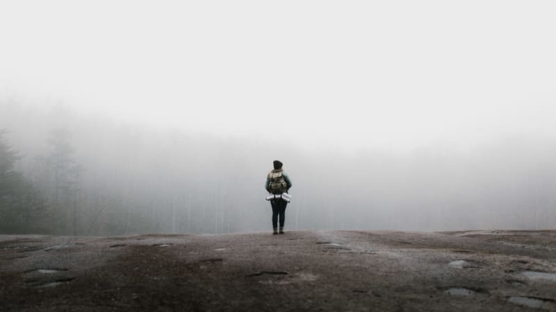 A solitary figure looking into the foggy expanse, symbolizing introspection and the contemplative journey through the past year.