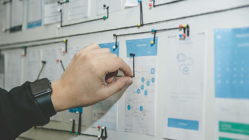 A detailed view of project management in action, showcasing a team member analyzing a user journey map to optimize the project's user flow.