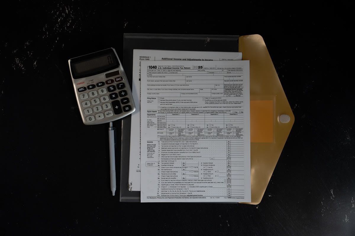 Business owner at a desk working through revenue figures on a calculator and notepad