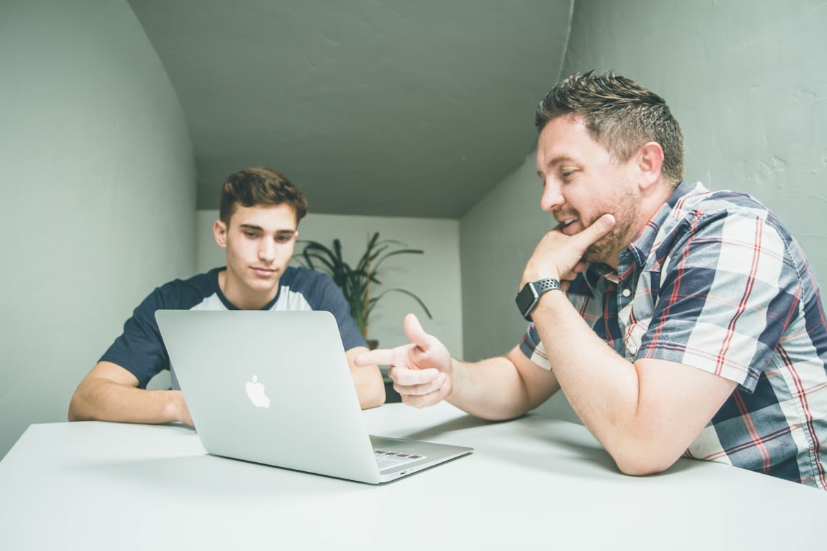 Private tutor sitting with a student at a desk with open books and notes
