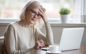 landlord pain points image: image of a woman with gray hair and glasses staring frustratedly at a screen with her hand on her head