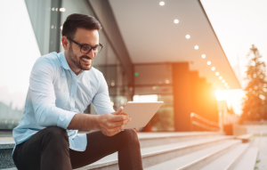 landlords in 2020 image: man smiling at ipad with sun setting in background