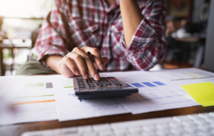 the cost of an eviction image: Picture of flannel-wearing woman's hands typing on calendar