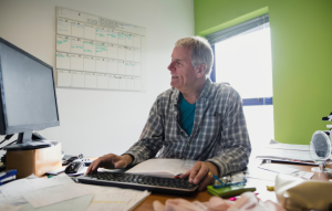 manage your rentals remotely image: picture of a 60-year old man in a flannel shirt working on the computer sitting at his desk