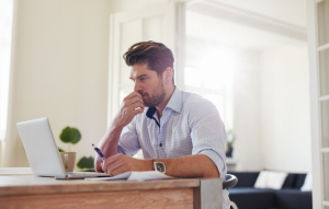 how to handle rent image: picture of a man sitting at his desk with a laptop open and looking concerned